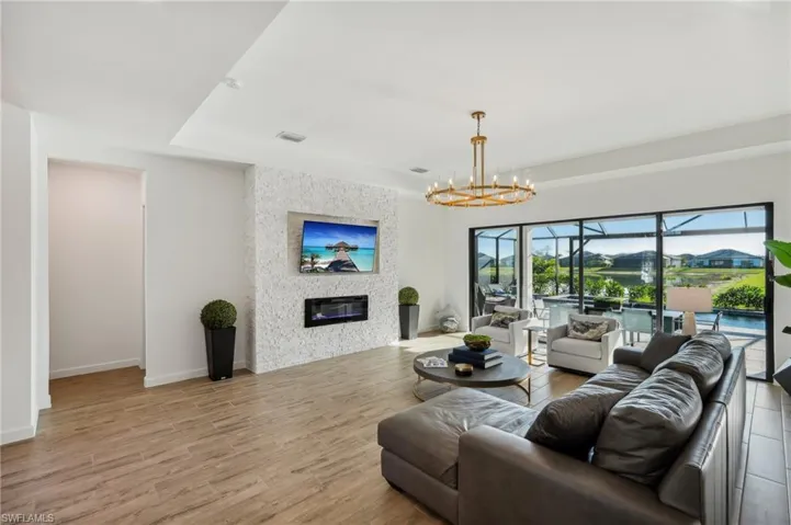 Living room featuring a large fireplace, a tray ceiling, light hardwood / wood-style floors, and a notable chandelier