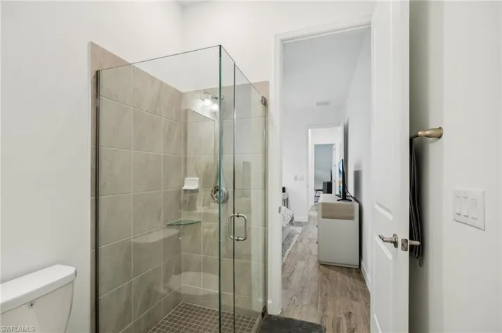 Bathroom featuring an enclosed shower, hardwood / wood-style flooring, and toilet