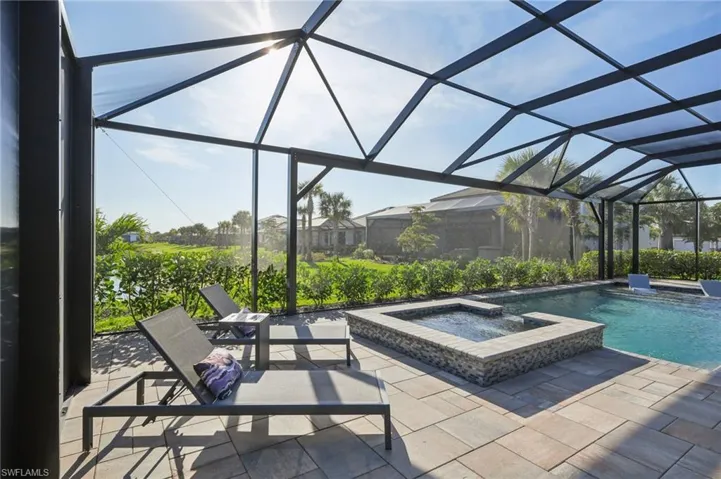 View of pool featuring an in ground hot tub, a patio area, and glass enclosure