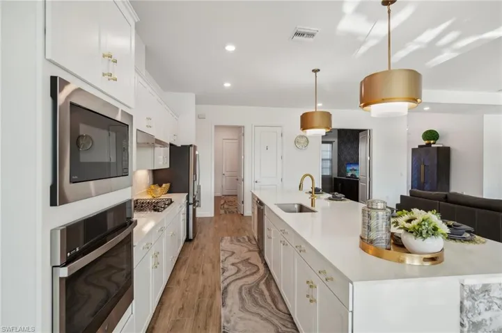 Kitchen with white cabinets, stainless steel appliances, sink, and a large island with sink