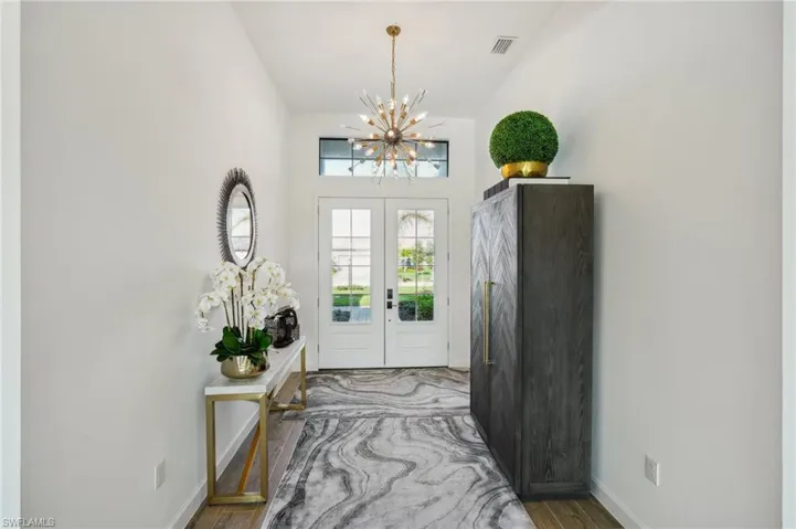 Entrance foyer featuring hardwood / wood-style flooring, a notable chandelier, and french doors