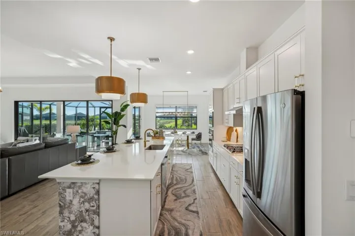 Kitchen featuring appliances with stainless steel finishes, sink, an island with sink, and white cabinets