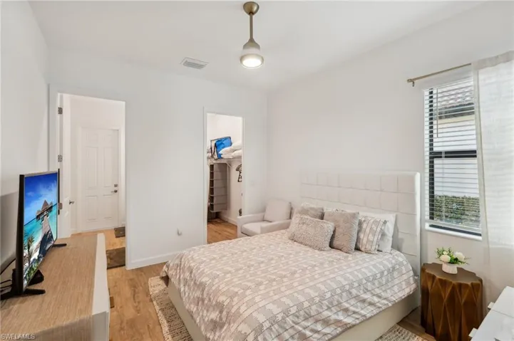 Bedroom with a walk in closet, light hardwood / wood-style floors, and a closet
