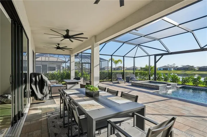 View of patio / terrace with a water view, ceiling fan, a swimming pool with hot tub, and a lanai