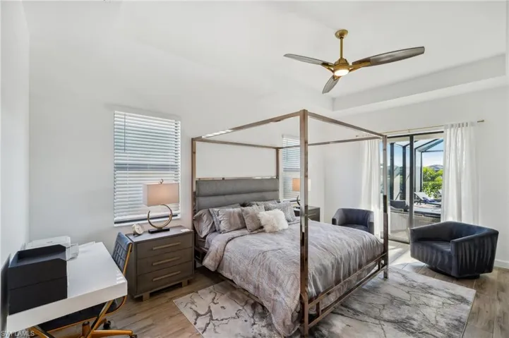 Bedroom featuring a raised ceiling, ceiling fan, access to exterior, and light hardwood / wood-style floors