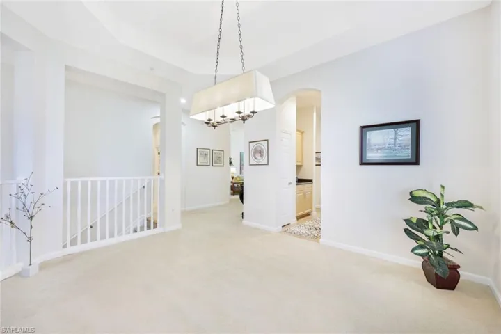 Spare room featuring light carpet, a chandelier, and arched walkways