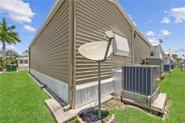 View of property exterior with a yard and central AC unit