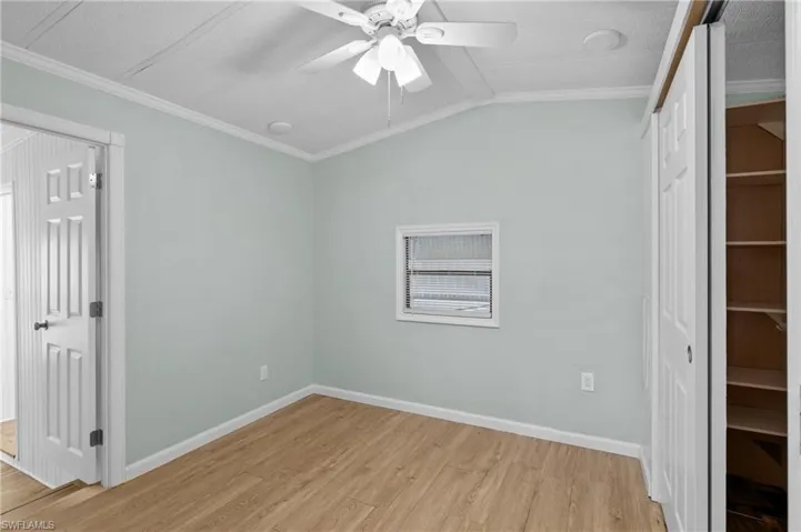 Empty room with ceiling fan, light hardwood / wood-style flooring, and crown molding