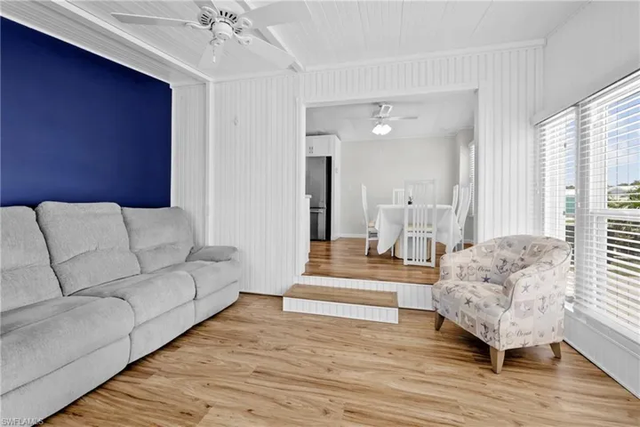 Living room with ceiling fan, hardwood / wood-style floors, and lofted ceiling