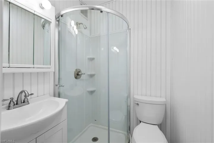 Bathroom featuring walk in shower, vanity, and toilet