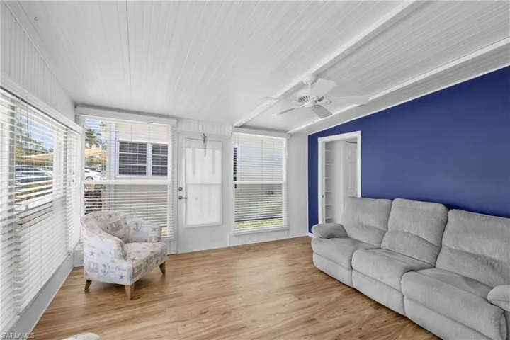 Living room with beamed ceiling, ceiling fan, and light hardwood / wood-style floors