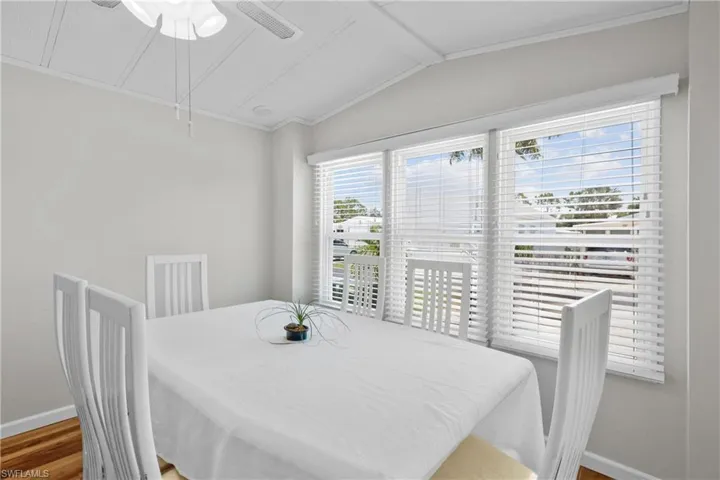 Dining space featuring ceiling fan, vaulted ceiling, ornamental molding, and wood-type flooring