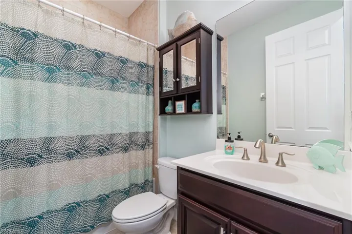 Full bath with vanity and curtained shower.