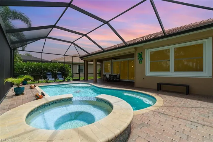 Pool at dusk featuring a patio, a pool with connected hot tub, ceiling fan, and a lanai