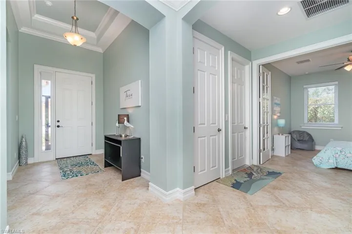 Foyer entrance featuring crown molding, tile patterned flooring, ceiling fan, and arched walkways