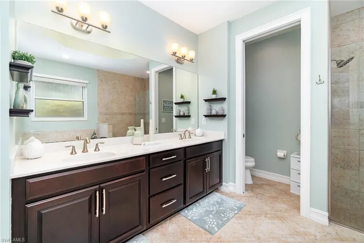 Bathroom featuring a large walk-in showing, soaking tub, double vanity, tiled shower, tile floors and a water closet.