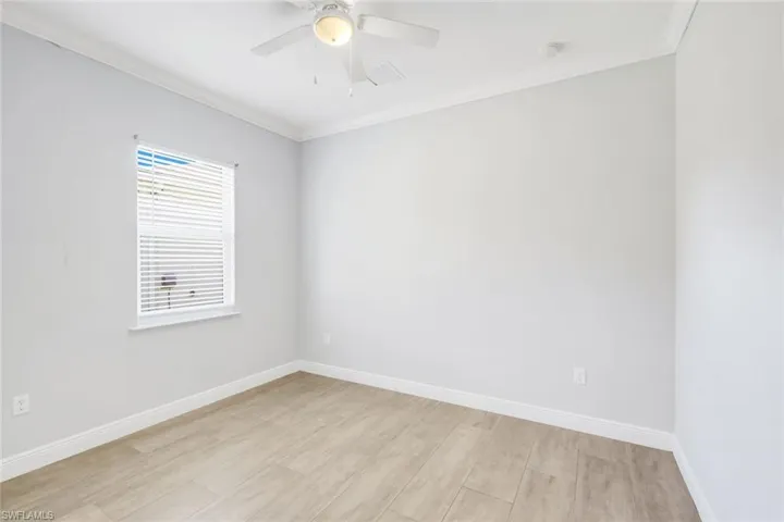 Empty room with ornamental molding, light wood-style flooring, and ceiling fan