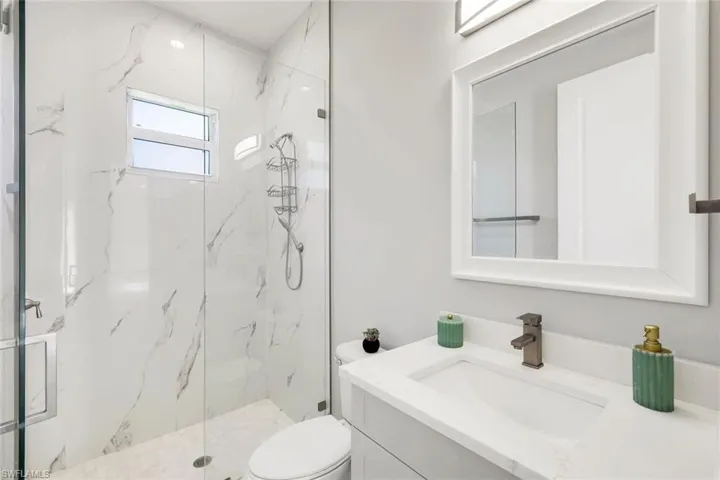 Bathroom with vanity and a marble finish shower