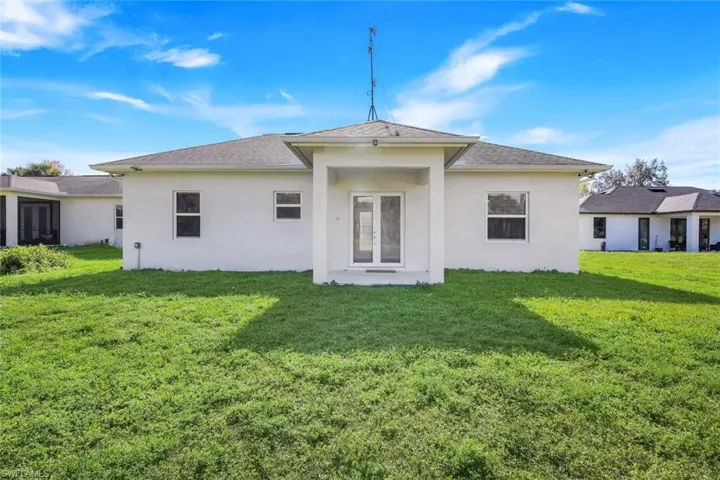 Back of property with stucco siding, a lawn, and a patio area