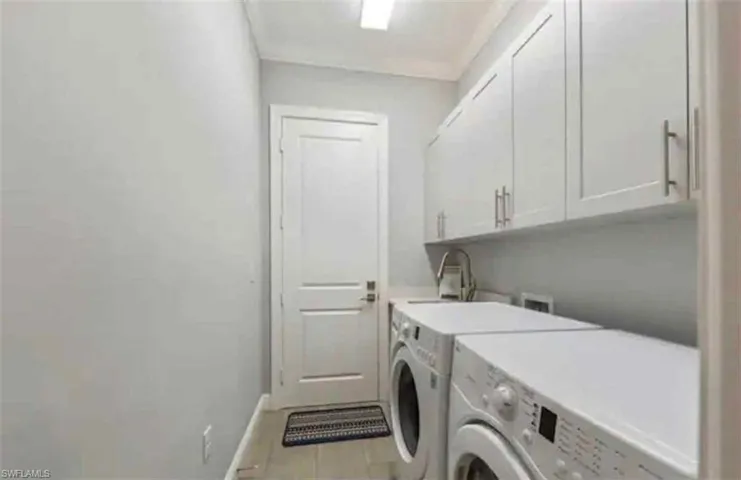 Laundry area with cabinet space, separate washer and dryer, and light tile patterned floors