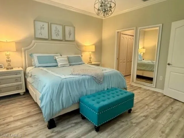 Bedroom featuring crown molding, a chandelier, wood finished floors, and a closet
