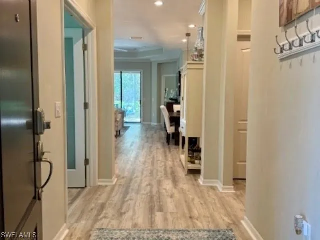 Hallway with light wood-type flooring and recessed lighting