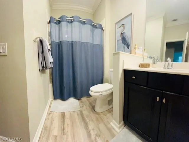 Bathroom with crown molding, wood finished floors, vanity, and shower / bath combo