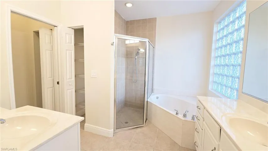 Bathroom with tile patterned floors, a sink, two vanities, and a shower stall