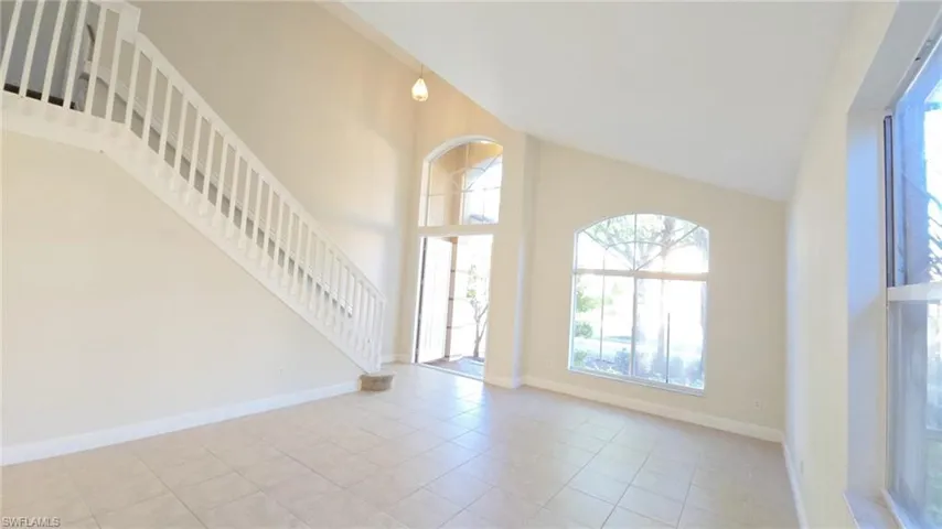 Foyer entrance featuring stairs, high vaulted ceiling, tile patterned flooring, and baseboards