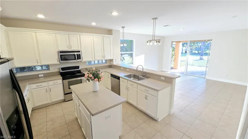 Kitchen featuring light countertops, a peninsula, stainless steel appliances, recessed lighting, and a sink