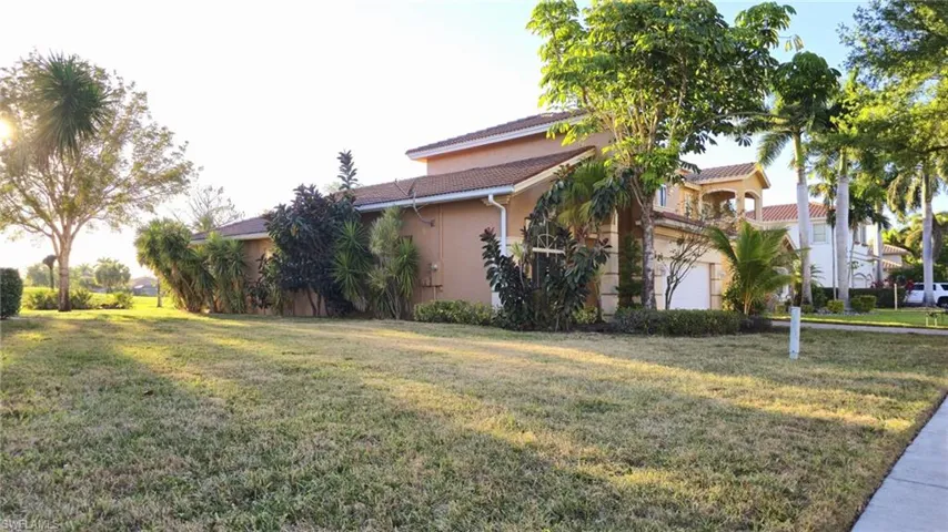 View of property exterior featuring a tiled roof, a garage, stucco siding, and a yard
