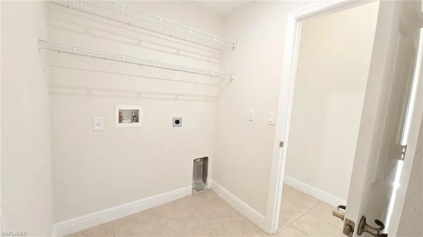 Laundry area featuring light tile patterned flooring, washer hookup, baseboards, laundry area, and hookup for an electric dryer
