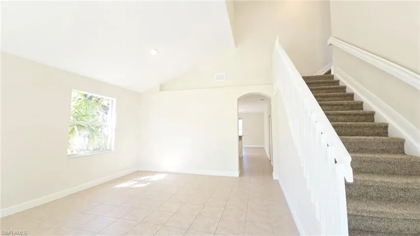 Stairway featuring baseboards, visible vents, arched walkways, and tile patterned flooring