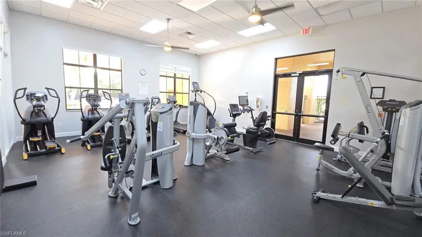 Exercise room with french doors, a paneled ceiling, a ceiling fan, and a wealth of natural light