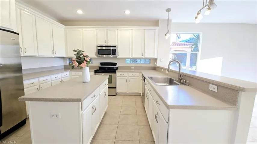 Kitchen featuring light tile patterned flooring, light countertops, a sink, white cabinetry, and stainless steel appliances