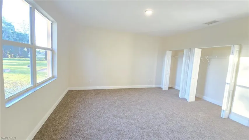 Unfurnished bedroom with baseboards, multiple closets, visible vents, and light carpet