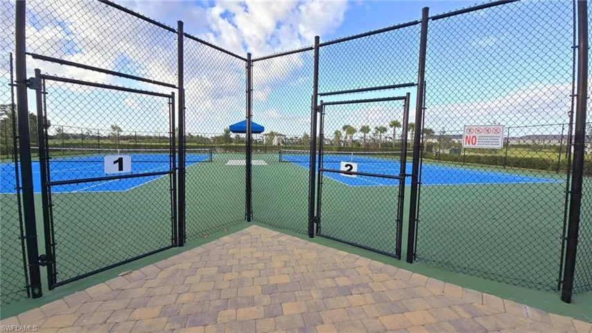 View of tennis court with a gate and fence