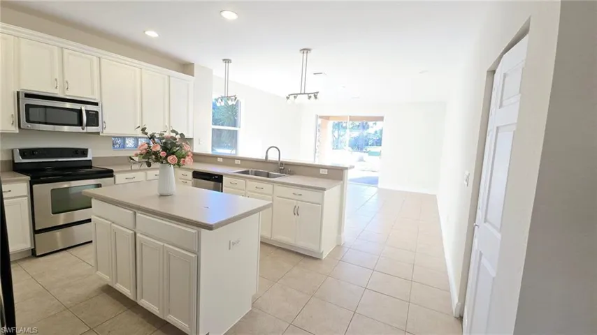 Kitchen featuring light tile patterned floors, a sink, stainless steel appliances, and a peninsula