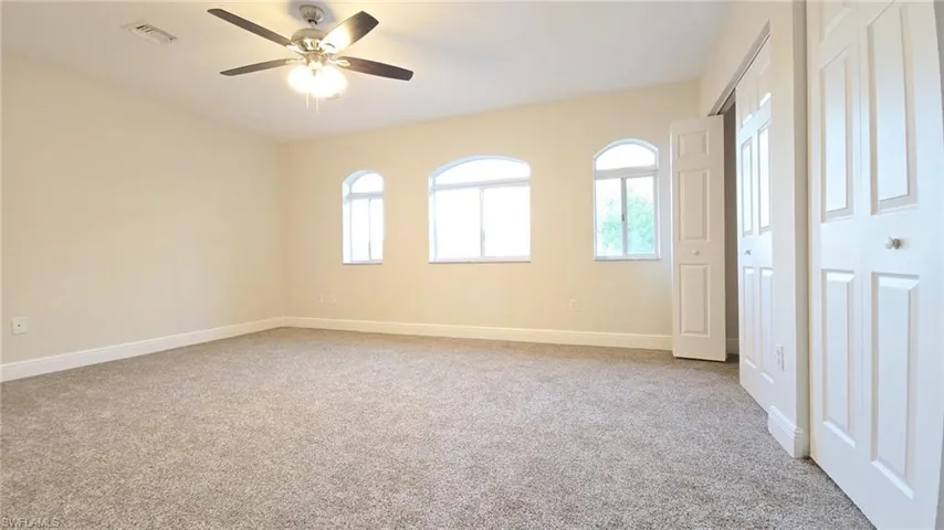 Unfurnished bedroom featuring baseboards, visible vents, ceiling fan, and carpet
