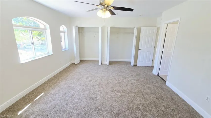 Unfurnished bedroom with baseboards, multiple closets, ceiling fan, and carpet flooring