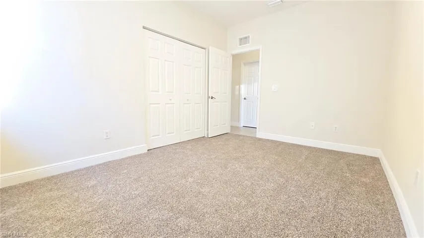 Unfurnished bedroom with carpet flooring, baseboards, a closet, and visible vents