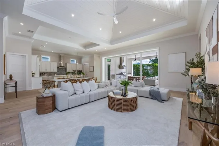 The open concept main living area features a vaulted ceiling with nickel gap and beam work, 10' impact pocket sliders, and Sub-Zero/Wolf kitchen appliance suite