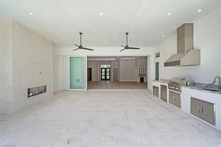 The outdoor covered living space provides ample space for comfy socializing, with a natural gas fireplace and full outdoor kitchen with gas grill, sink, under counter fridge, and storage. The covered living opening has been pre-wired for optional motorized roll down bug/storm screens.