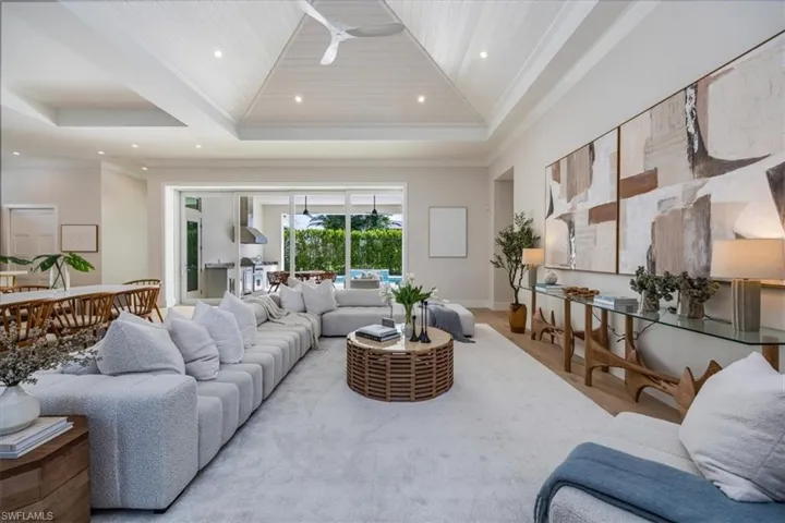 The open concept main living area features a vaulted ceiling with nickel gap and beam work, 10' impact pocket sliders, and Sub-Zero/Wolf kitchen appliance suite