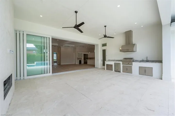 The outdoor covered living space provides ample space for comfy socializing, with a natural gas fireplace and full outdoor kitchen with gas grill, sink, under counter fridge, and storage. The covered living opening has been pre-wired for optional motorized roll down bug/storm screens.