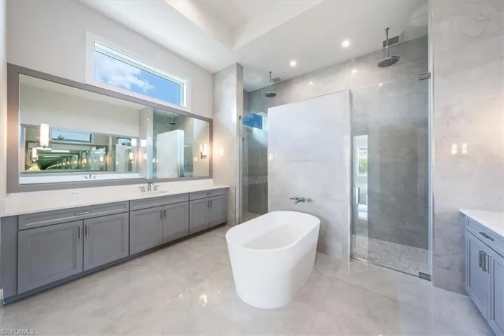The primary bathroom sparkles with large scale polished tile, oversized dual vanities, soaking tub, and 5-fixture shower with bench and rain showers. A private water closet completes the bath.