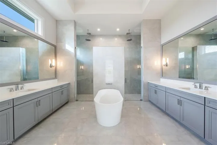 The primary bathroom sparkles with large scale polished tile, oversized dual vanities, soaking tub, and 5-fixture shower with bench and rain showers.