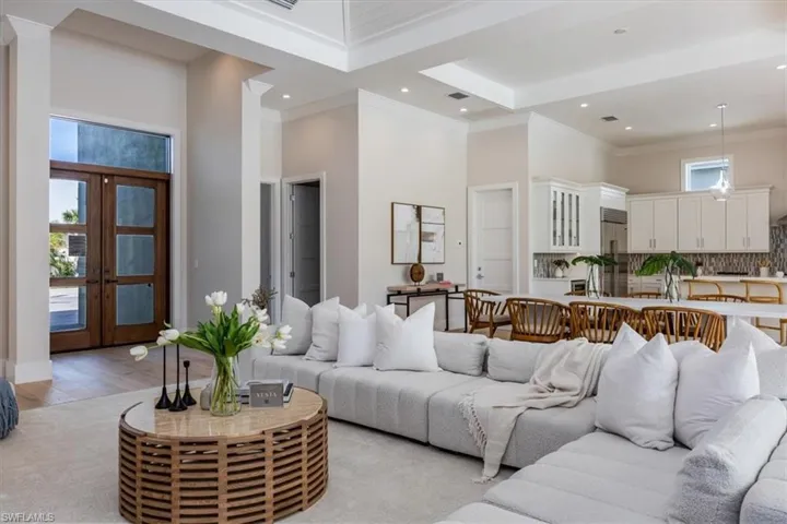 The open concept main living area features a vaulted ceiling with nickel gap and beam work, 10' impact pocket sliders, and Sub-Zero/Wolf kitchen appliance suite