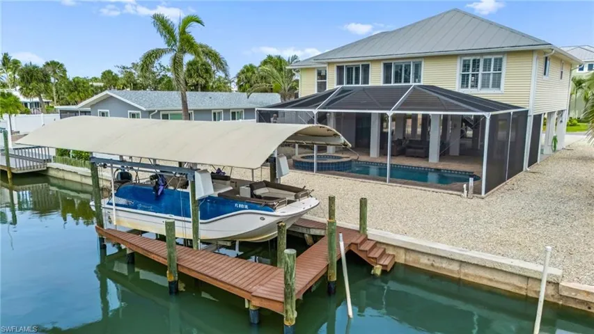 Dock area with boat lift, screened in pool and Gulf access canal - virtually enhanced