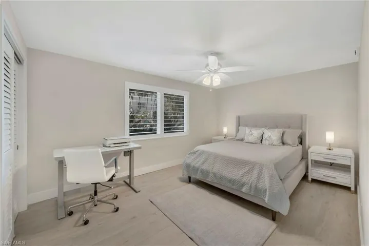 Bedroom featuring light wood-style flooring, a ceiling fan, a closet, and an office area